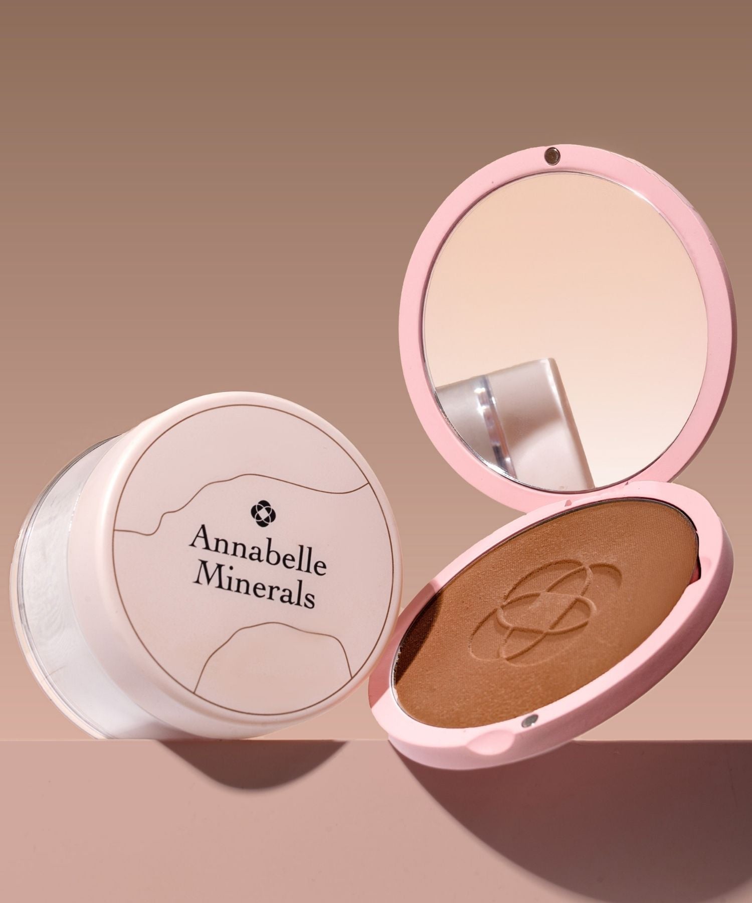 Różowa kompaktowa puderniczka Annabelle Minerals z lusterkiem i bronzerem wewnątrz obok podkładu mineralnego Annabelle Minerals w dużej pojemności