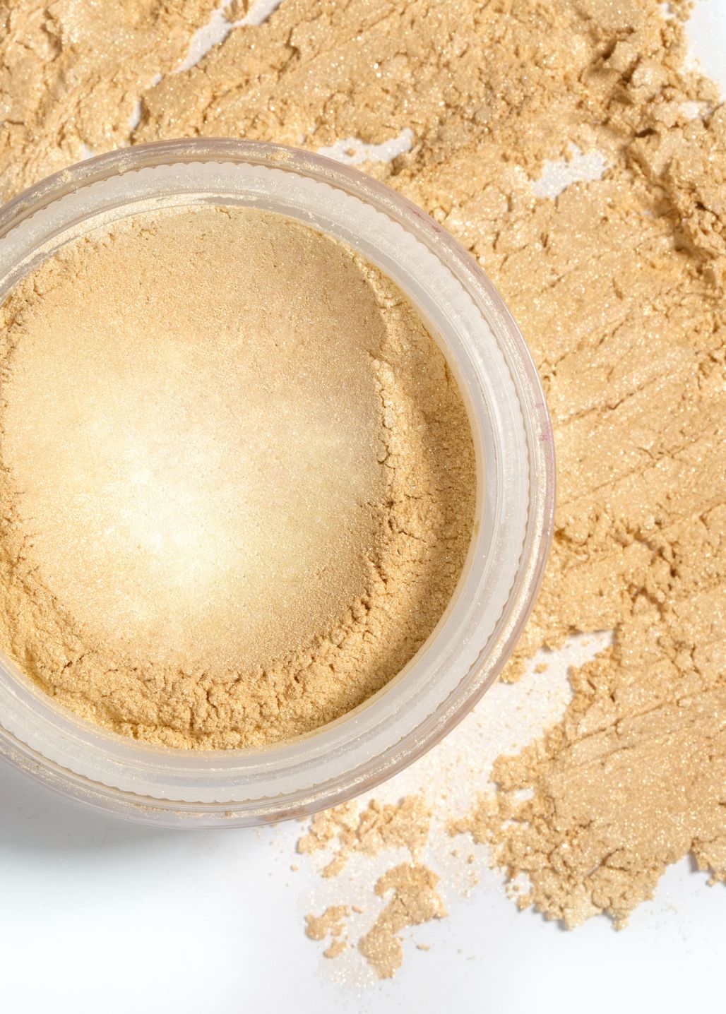 Zbliżenie na rozświetlacz mineralny Royal Glow Annabelle Minerals w złotym kolorze na tle swatcha  